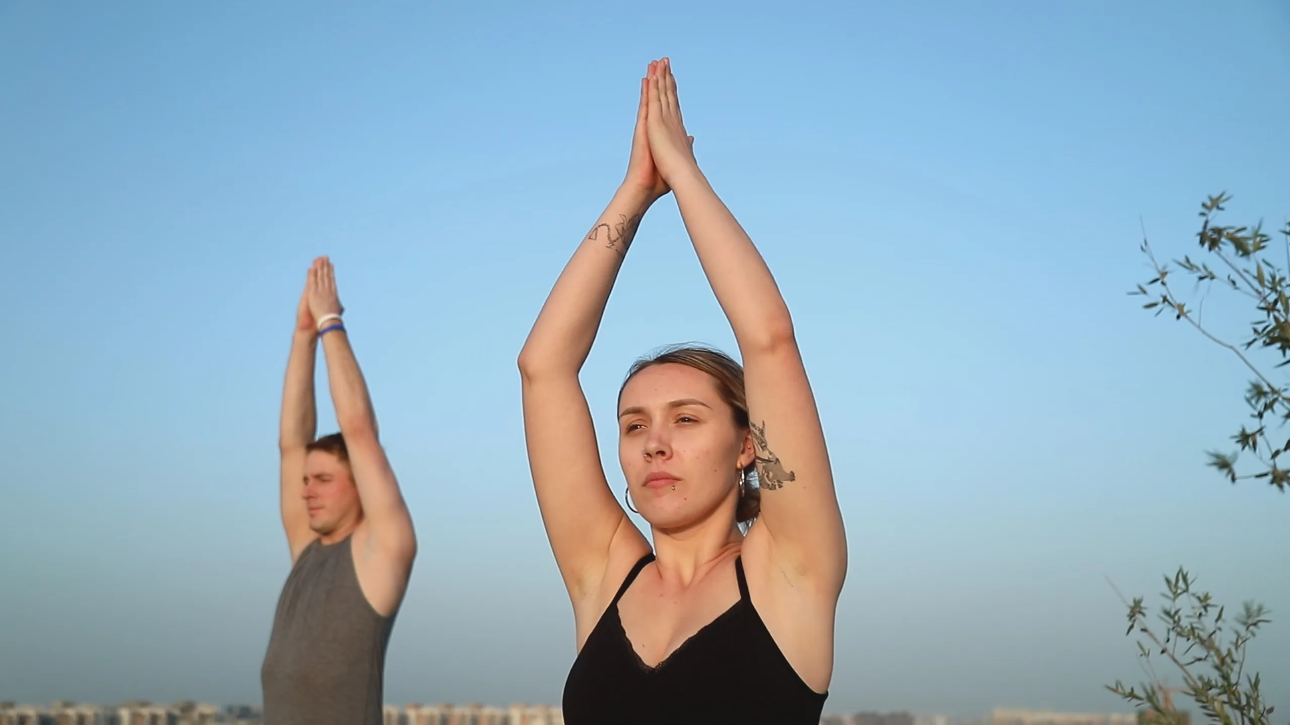 To personer udfører yoga i bønnestilling udendørs ved solnedgang – bevægelse og mental trivsel